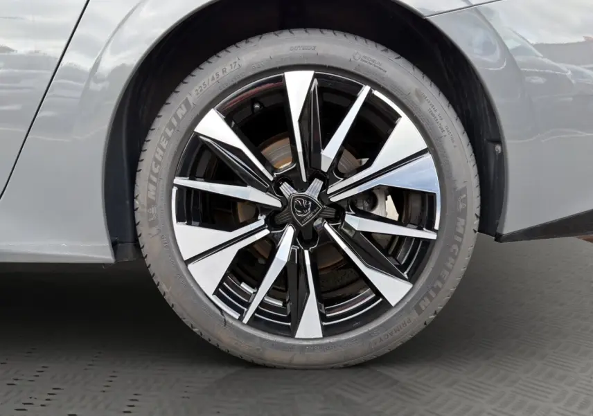 Gros plan sur la roue avant gauche de la Peugeot 308 Hybrid 145 e-DCS6 Allure gris foncé avec jante alliage bicolore.
