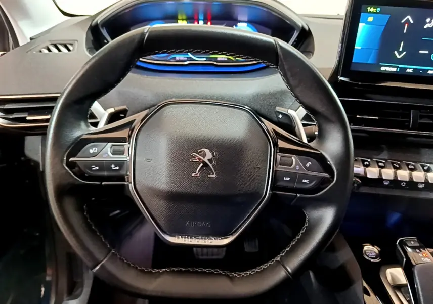 Vue rapprochée du volant cuir noir du Peugeot 3008 hybride 2021 avec tableau de bord digital et écran tactile.