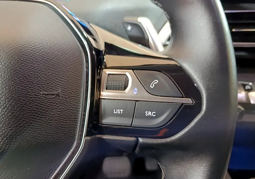 Gros plan sur les commandes gauche du volant cuir noir du Peugeot 3008 hybride rechargeable bleu 2021.