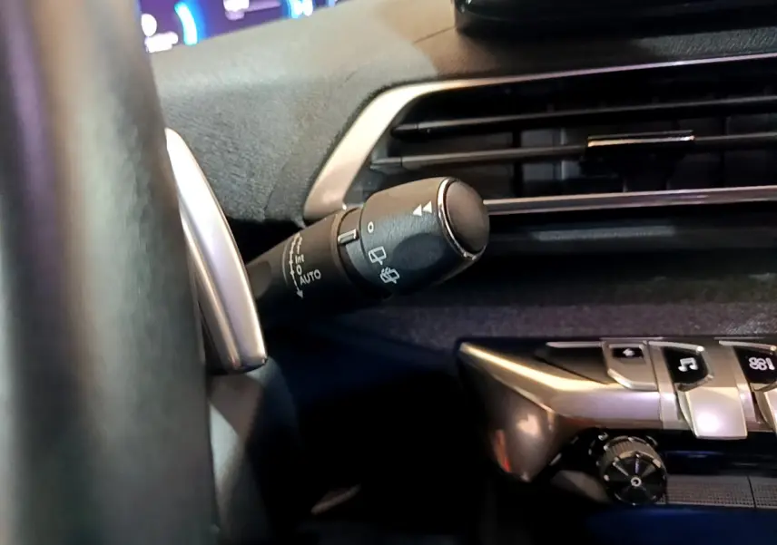 Gros plan sur la commande d'essuie-glace côté gauche du tableau de bord noir du Peugeot 3008 hybride bleu 2021.