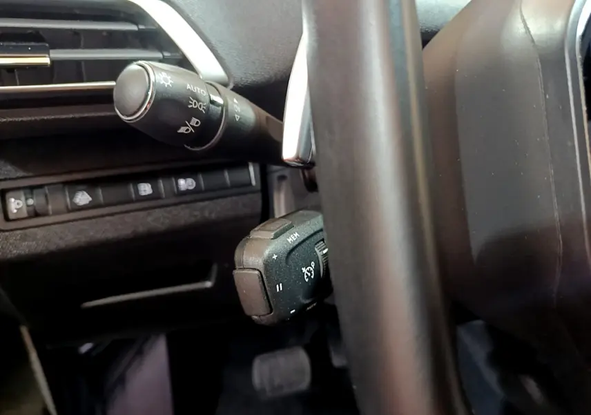 Gros plan sur le volant noir et la commande de régulateur de vitesse du Peugeot 3008 hybride rechargeable.