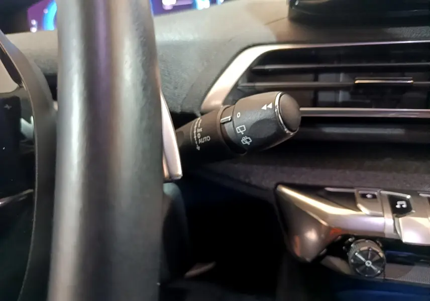 Détail intérieur du Peugeot 3008 bleu 2021 montrant le commodo d'essuie-glace et partie du tableau de bord côté conducteur.