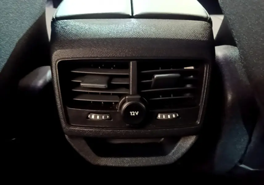 Gros plan sur la sortie d'air arrière noire avec prise 12V du Peugeot 3008 hybride rechargeable bleu 2021.