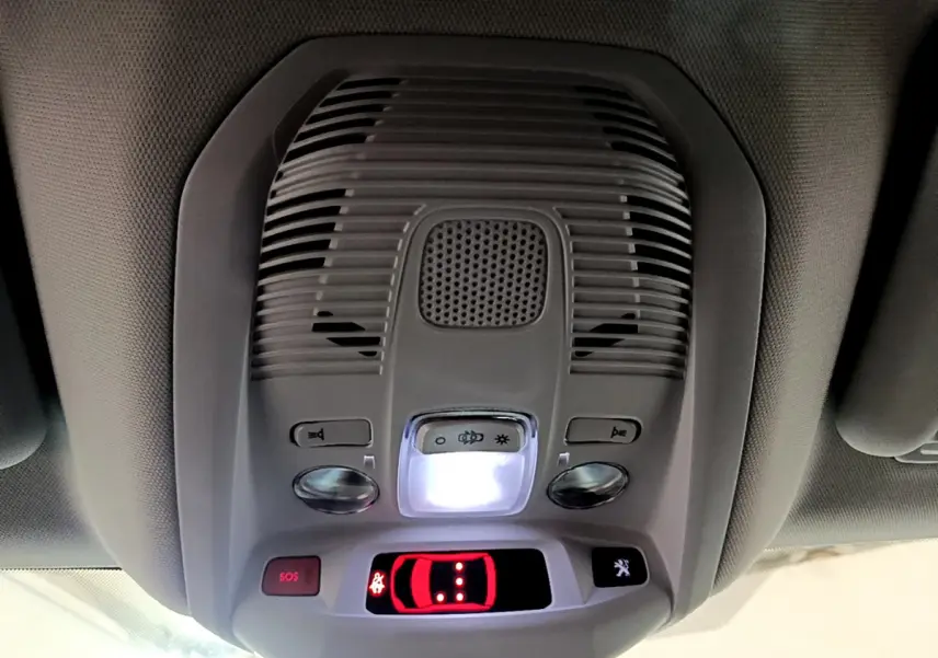 Vue en gros plan du plafonnier intérieur gris du Peugeot 3008 hybride rechargeable avec boutons SOS et éclairage central allumé.