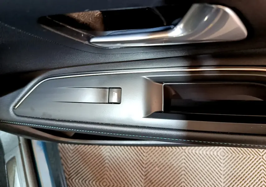 Poignée intérieure côté gauche en plastique noir et métal brossé du Peugeot 3008 hybride rechargeable bleu 2021.