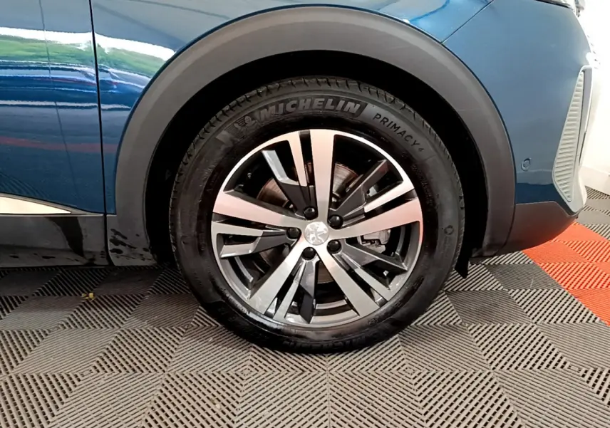 Gros plan sur la roue avant gauche d’un Peugeot 3008 bleu avec jante alliage et pneu Michelin Primacy.
