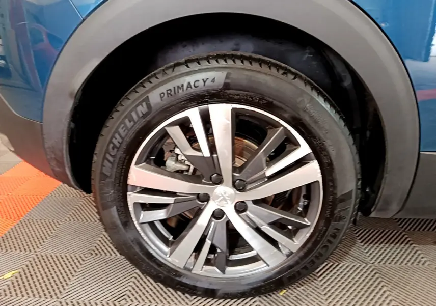 Gros plan sur la roue avant gauche du Peugeot 3008 bleu hybride avec jante alliage et pneu Michelin Primacy 4.