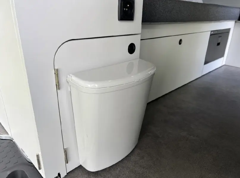 Détail intérieur montrant un petit bac blanc intégré au mobilier gris clair du fourgon aménagé Renault Trafic Fourgon gris.