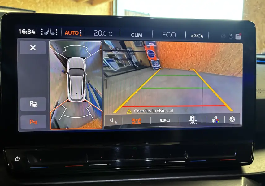 Écran tactile intérieur montrant la caméra de recul et l'aide au stationnement du CUPRA Formentor bleu hybride.