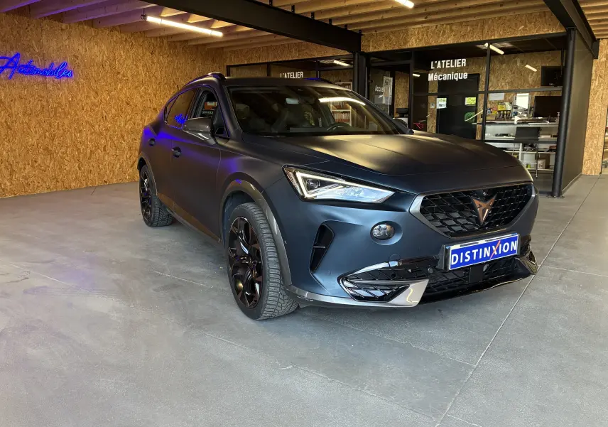 Vue 3/4 avant droite d'une CUPRA Formentor 1.4 e-Hybrid 245 bleu mat avec jantes noires en intérieur d'atelier.