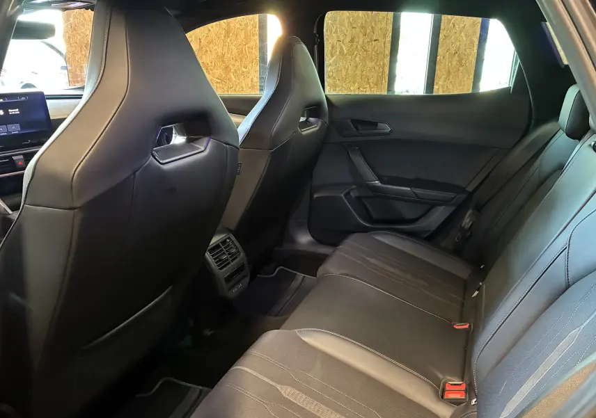 Vue intérieure arrière de la CUPRA Formentor 1.4 e-Hybrid 2023, sièges sport noirs en tissu et similicuir avec surpiqûres copper.