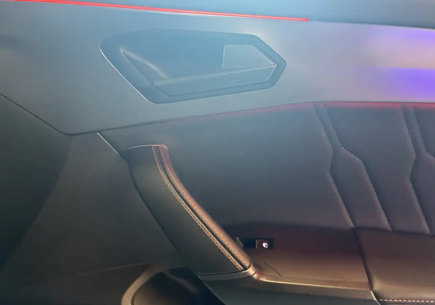 Détail de la porte intérieure côté droit de la CUPRA Formentor bleu, avec surpiqûres et éclairage d'ambiance rouge.