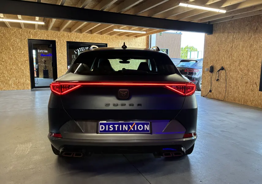 Vue arrière d'un CUPRA Formentor bleu 2023 avec feux LED allumés et double sortie d'échappement rectangulaire.