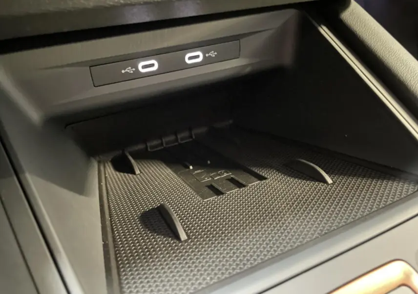 Gros plan sur l'espace de rangement central avec deux ports USB-C éclairés dans l'habitacle noir du CUPRA Leon 2026.