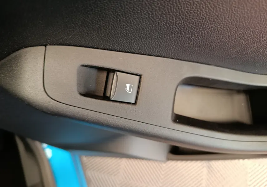 Bouton de commande de lève-vitre côté conducteur sur porte intérieure noire du Ford Puma bleu 2025.