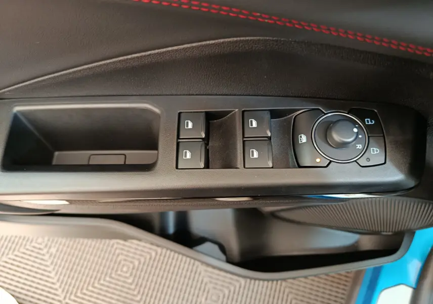 Gros plan sur les commandes de lève-vitres et rétroviseurs côté conducteur du Ford Puma bleu 2025.