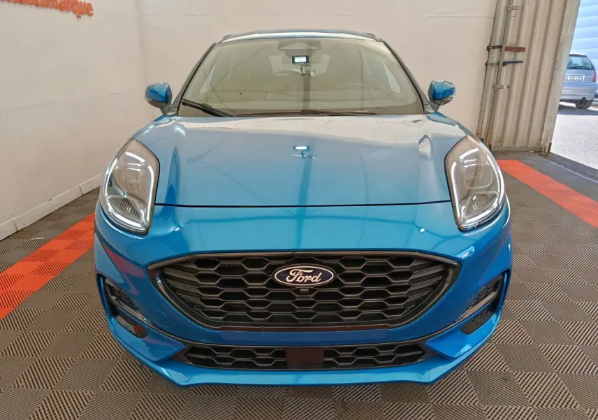 Vue frontale d'une Ford Puma bleue 2025 avec calandre noire hexagonale et phares LED distinctifs.