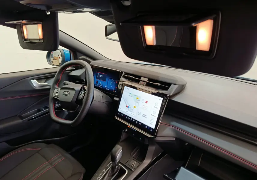 Vue intérieure côté conducteur du Ford Puma 2025 bleu, tableau de bord moderne avec écran tactile et volant cuir noir.