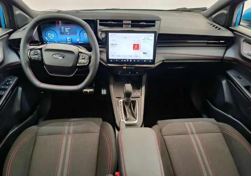 Vue intérieure avant du Ford Puma bleu 2025, tableau de bord moderne avec écran tactile central et volant multifonctions.
