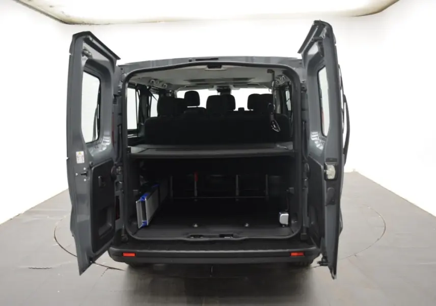 Vue arrière du Renault Trafic Fourgon gris clair 2025, portes ouvertes montrant l’espace de chargement et la banquette arrière.