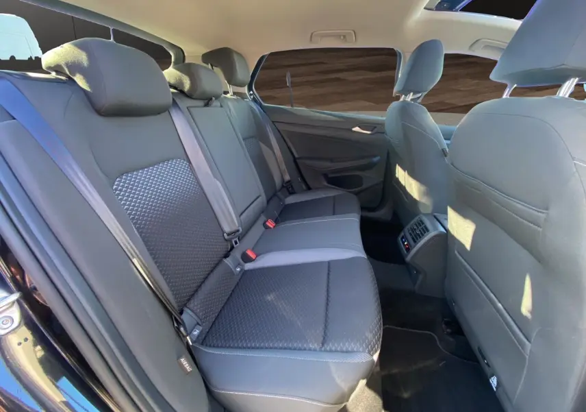 Vue intérieure arrière côté droit de la Volkswagen Golf VIII noire, montrant les sièges arrière et le toit panoramique.