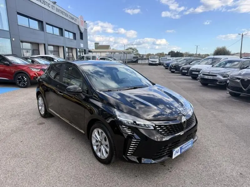 Renault Clio V noire vue en 3/4 avant droit, avec calandre moderne et feux LED distinctifs, stationnée en extérieur.