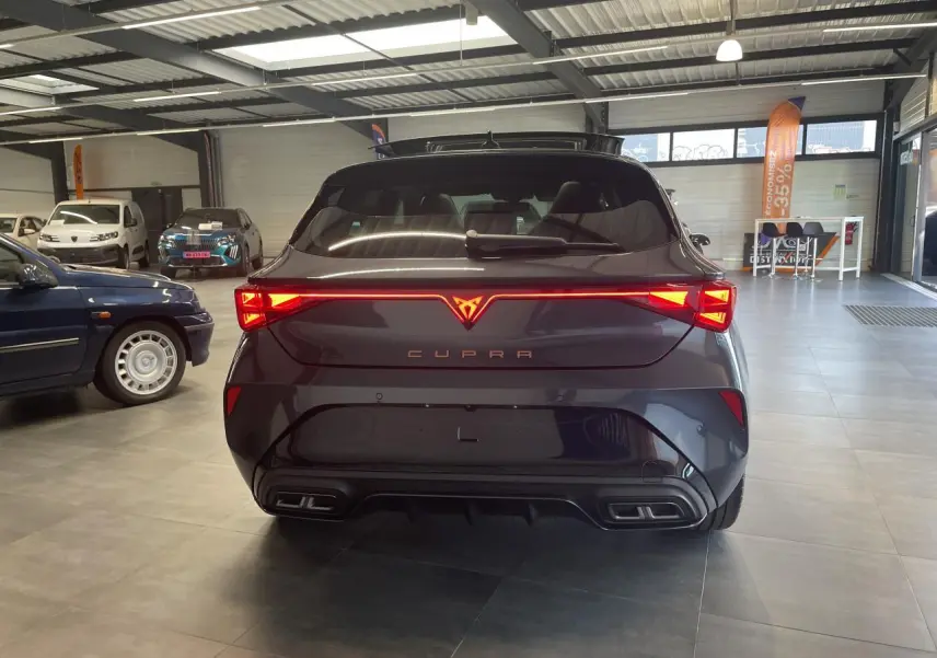 Vue arrière d'une CUPRA Leon gris magnétique avec feux arrière Tri-LED et double sortie d'échappement noire stylisée.