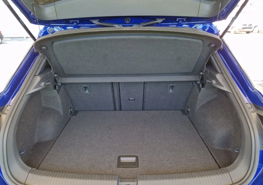Coffre ouvert du Volkswagen T-Roc bleu Lapiz, vue de l'arrière montrant un espace de chargement propre et spacieux.