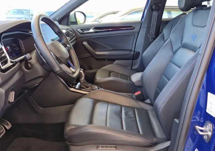 Vue intérieure côté conducteur du Volkswagen T-Roc bleu Lapiz 2022 avec sièges cuir et volant multifonction.