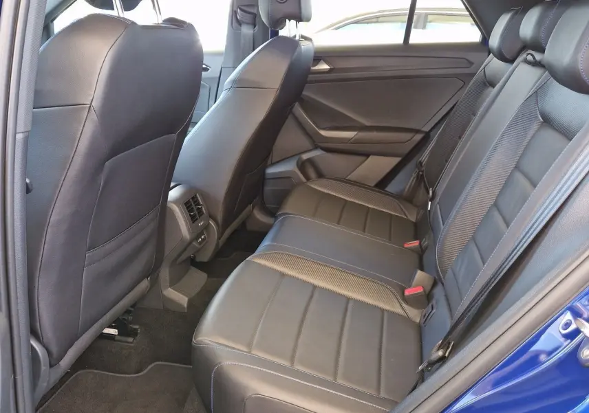 Vue intérieure arrière côté gauche du Volkswagen T-Roc bleu Lapiz avec sièges en cuir noir et finitions soignées.