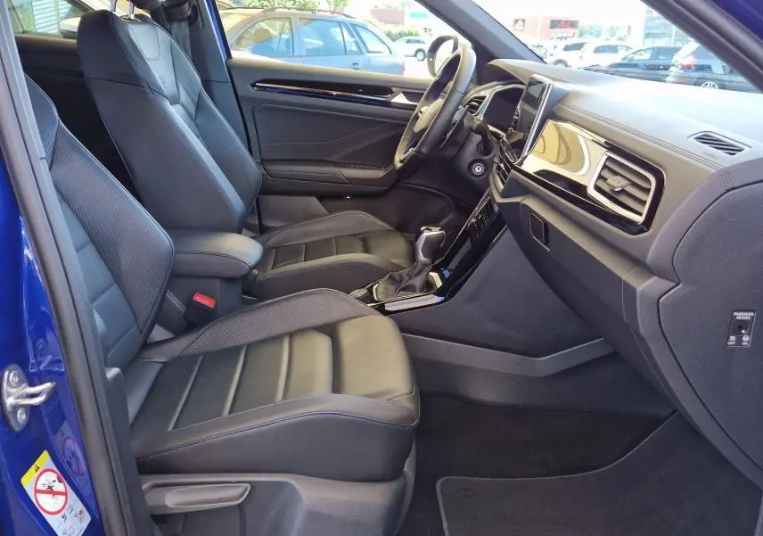 Intérieur du Volkswagen T-Roc bleu Lapiz 2022, vue côté gauche montrant les sièges en cuir et le tableau de bord moderne.