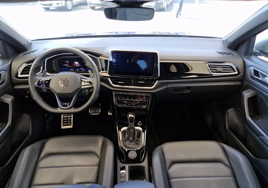 Intérieur du Volkswagen T-Roc 2022 en cuir noir, vue frontale du poste de conduite avec écran tactile central.