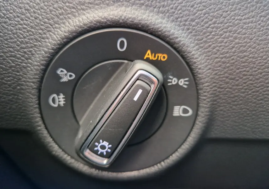 Gros plan sur le sélecteur d'éclairage noir du Volkswagen T-Roc 2022, avec mode auto et symboles lumineux blancs.