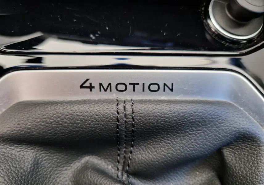 Gros plan sur le levier de vitesses cuir noir avec l'inscription 4MOTION dans l'habitacle du Volkswagen T-Roc bleu Lapiz.