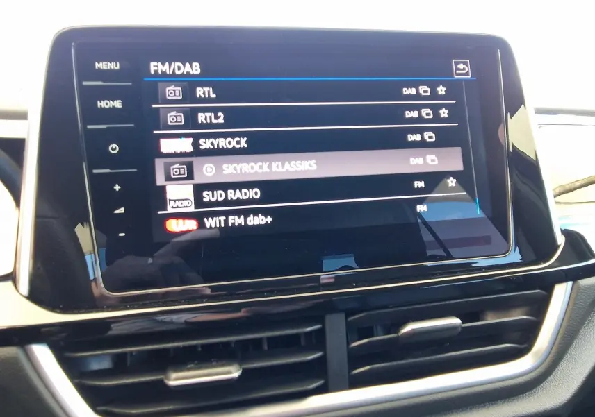 Écran tactile central du Volkswagen T-Roc 2022 affichant les stations radio FM/DAB avec commandes tactiles et aérateurs en dessous.