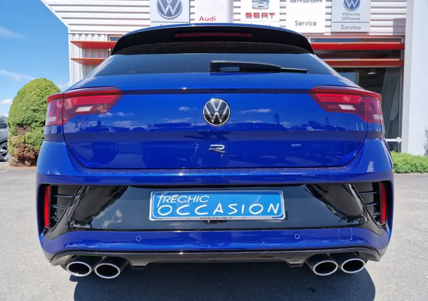 Vue arrière d'un Volkswagen T-Roc R bleu Lapiz avec double sortie d'échappement et logo distinctif R visible.
