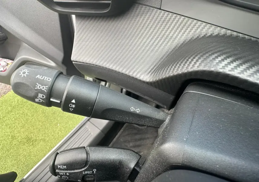 Détail des commandes de phares et régulateur sur la colonne de direction d'un Peugeot 2008 gris clair 2022.