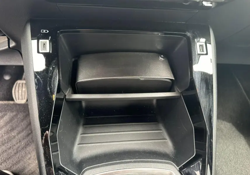 Gros plan sur la console centrale noire brillante du Peugeot 2008 II, avec prises USB visibles de chaque côté.