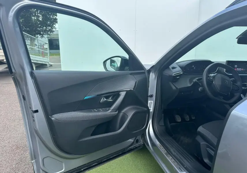 Intérieur avant gauche du Peugeot 2008 gris clair 2022, montrant porte ouverte et tableau de bord moderne.