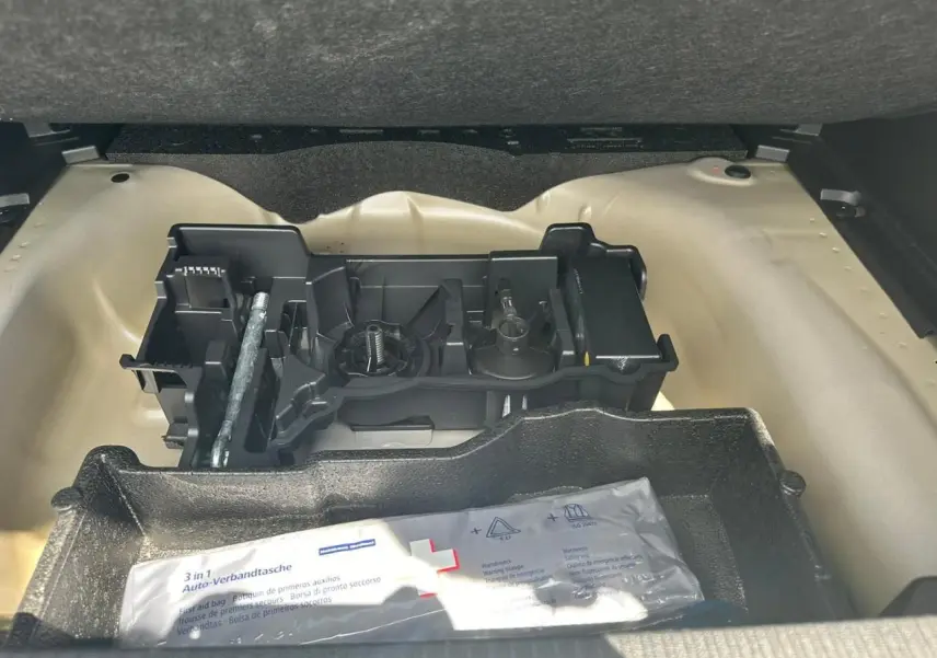 Coffre ouvert d'une Peugeot 2008 gris clair montrant le rangement sous plancher avec kit de dépannage pneumatique.