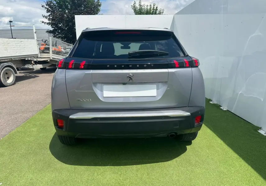 Vue arrière d'un Peugeot 2008 gris clair avec feux arrière à trois griffes rouges et becquet noir brillant.