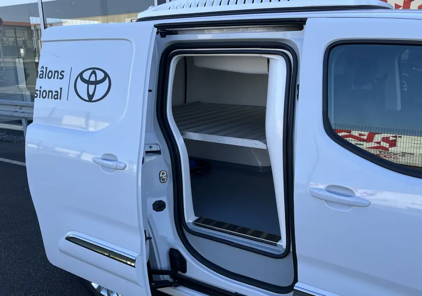 Vue latérale gauche d'un Toyota Proace City blanc glacier avec porte coulissante ouverte révélant l'espace frigorifique intérieur.