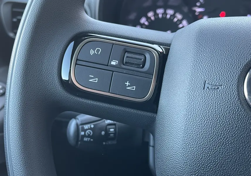Gros plan sur les commandes du volant à gauche du Toyota Proace City blanc glacier, montrant les boutons de volume et appel.