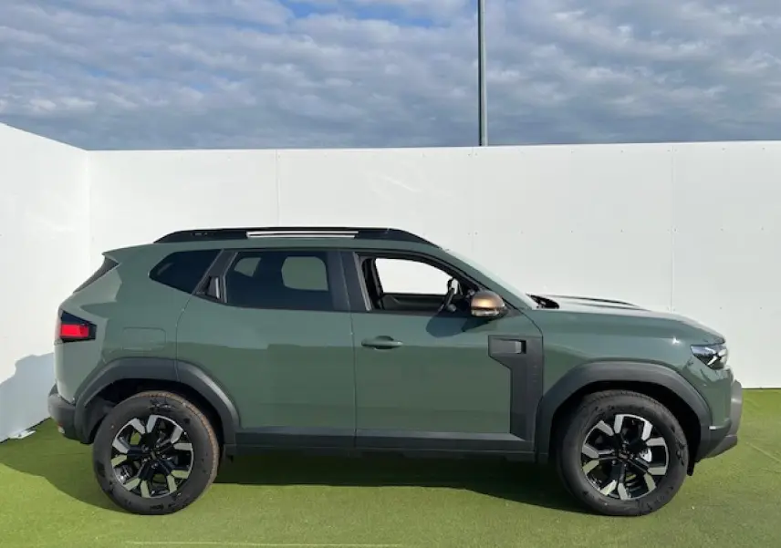 Profil côté gauche du Dacia Duster III 1.6 Hybrid 140 4x2 Extreme 2025 en kaki dusty avec jantes alliage 17 pouces.