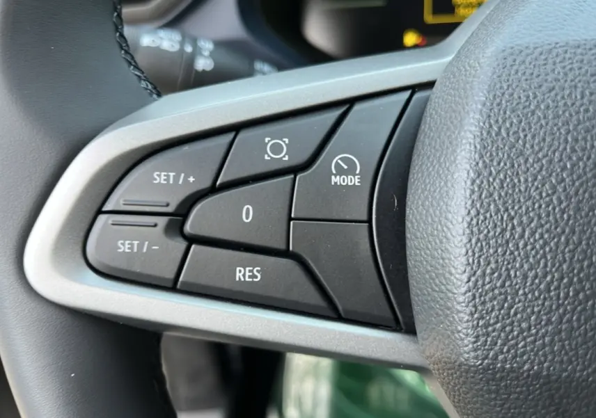 Gros plan sur les commandes de régulateur au volant cuir du Dacia Bigster Hybrid 155 Expression Plus, intérieur noir.