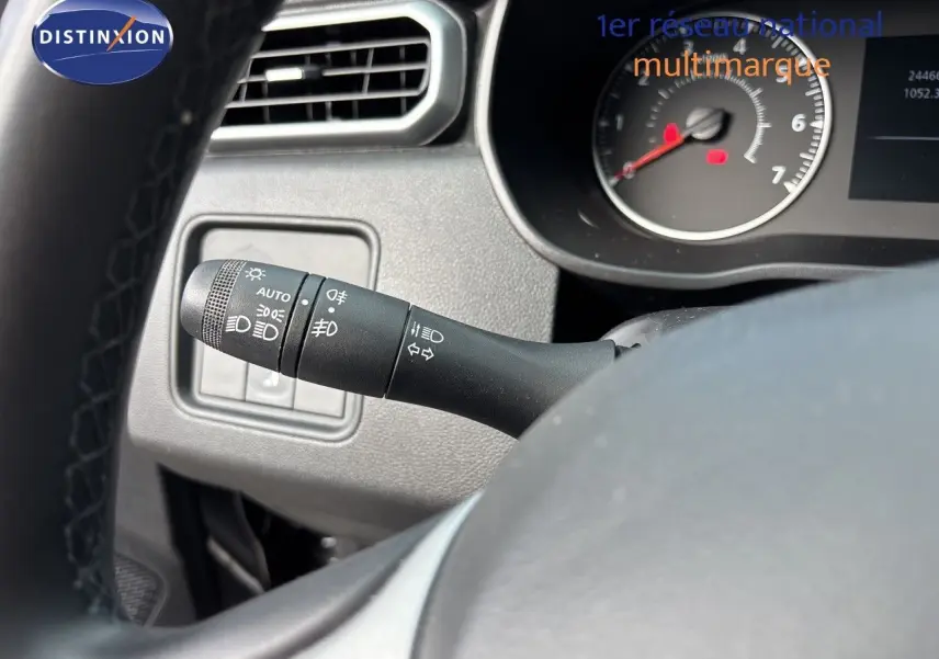 Gros plan sur la commande des phares à gauche du volant dans l'habitacle du Dacia Duster noir 2024.