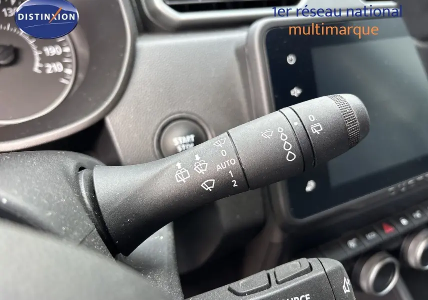 Gros plan sur la commande des essuie-glaces à l'intérieur du Dacia Duster noir, avec tableau de bord et écran tactile en arrière-plan.