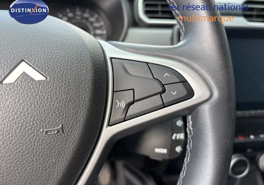Gros plan sur le volant noir du Dacia Duster 2024, mettant en valeur les commandes multifonctions côté droit.
