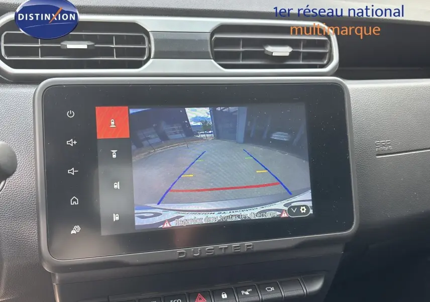Écran central du Dacia Duster 2024 noir montrant la caméra de recul avec lignes de guidage colorées.