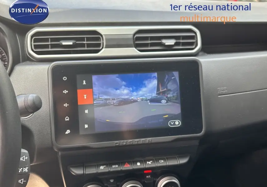 Intérieur du Dacia Duster 2024 noir, vue sur l’écran central tactile affichant la caméra de recul et la console de climatisation.
